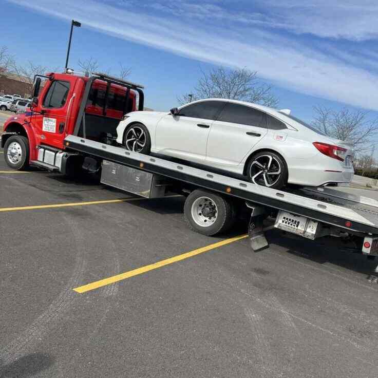 Full down recovery truck carrying a white sedan in Dubai